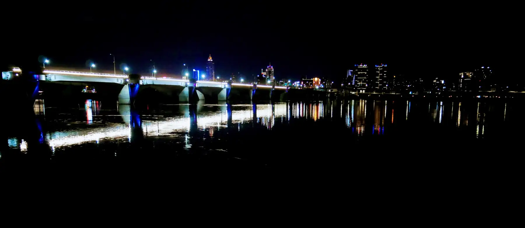 夜裡的河岸，橋上的燈光倒映在水面